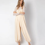 Model wearing a beige jumpsuit. She's standing behind a white background. The purpose of this image is to highlight the jumpsuit, which is available at EVAMAIA boutique in Los Angeles.