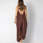 Model wearing a brown jumpsuit. She's standing behind a white background. The purpose of this image is to highlight the jumpsuit, which is available at EVAMAIA boutique in Los Angeles.