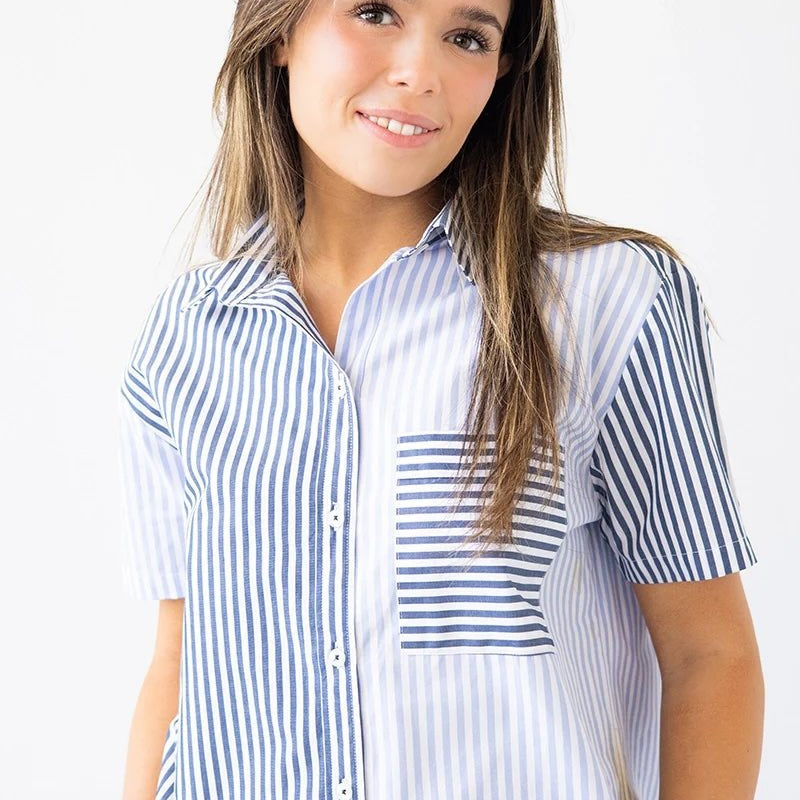 Woman wearing a blue and white striped shirt. She's standing against a white background. The purpose of this image is to highlight the clothing. 