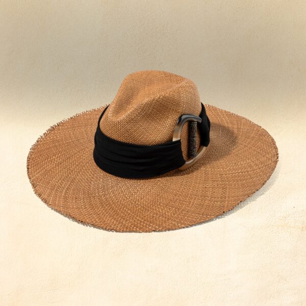 Brown wide brimmed hat with a black band and silver accent on a beige background