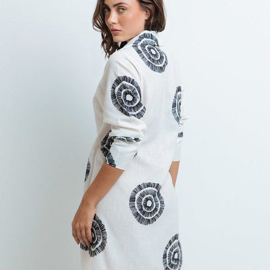 Woman wearing a black and white dress with a tie on the front. The purpose of this image is to highlight the dress because it is for sale at EVAMAIA boutique in Studio City, CA.