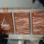Three Spinnaker chocolate bars in a clear plastic holder with a blurred background.