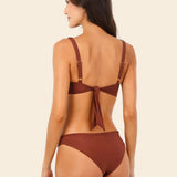 Woman wearing a brown bikini set on a beige background