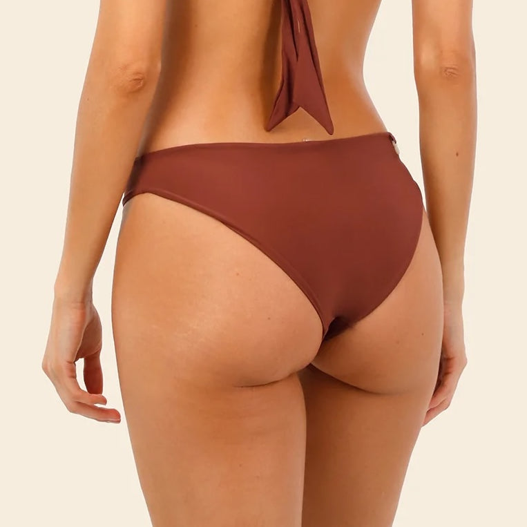 Woman wearing a brown bikini bottom on a beige background