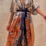 Woman wearing a floral and tiger print kimono with a plain background. 