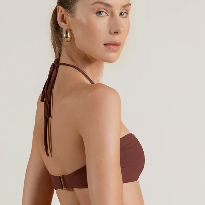 Woman wearing a brown bikini top against a plain background.
