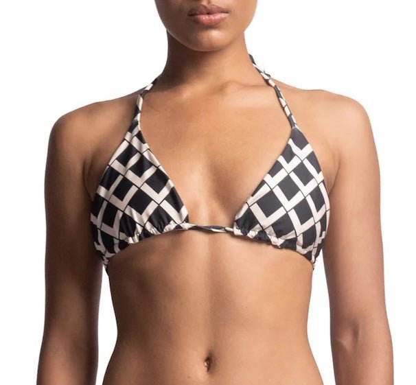 Close up of a woman wearing a black and white bikini top. She's in front of a white background. The purpose of this image is to highlight the bikini, which is available for sale at EVAMAIA Boutique in Studio City, CA.