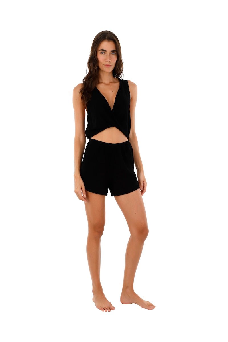 Image of a woman wearing a romper with a cutout on the front. This is the Black Halo Romper by Malai Swimwear. The purpose of the image is to highlight the romper.