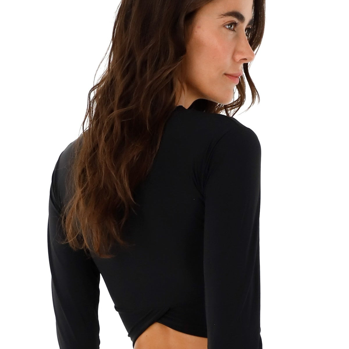 Woman wearing a black rashguard and swimsuit bottoms. She's standing against a white background. The purpose of this image is to highlight the swimsuit.