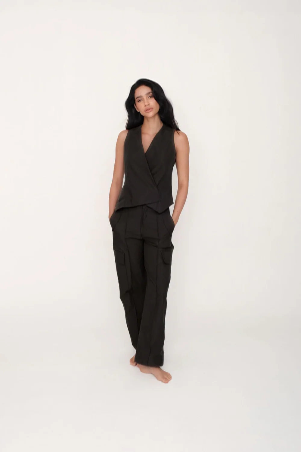 Woman wearing a black sleeveless top and pants on a white background