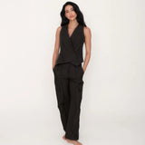 Woman wearing a black sleeveless top and pants on a white background