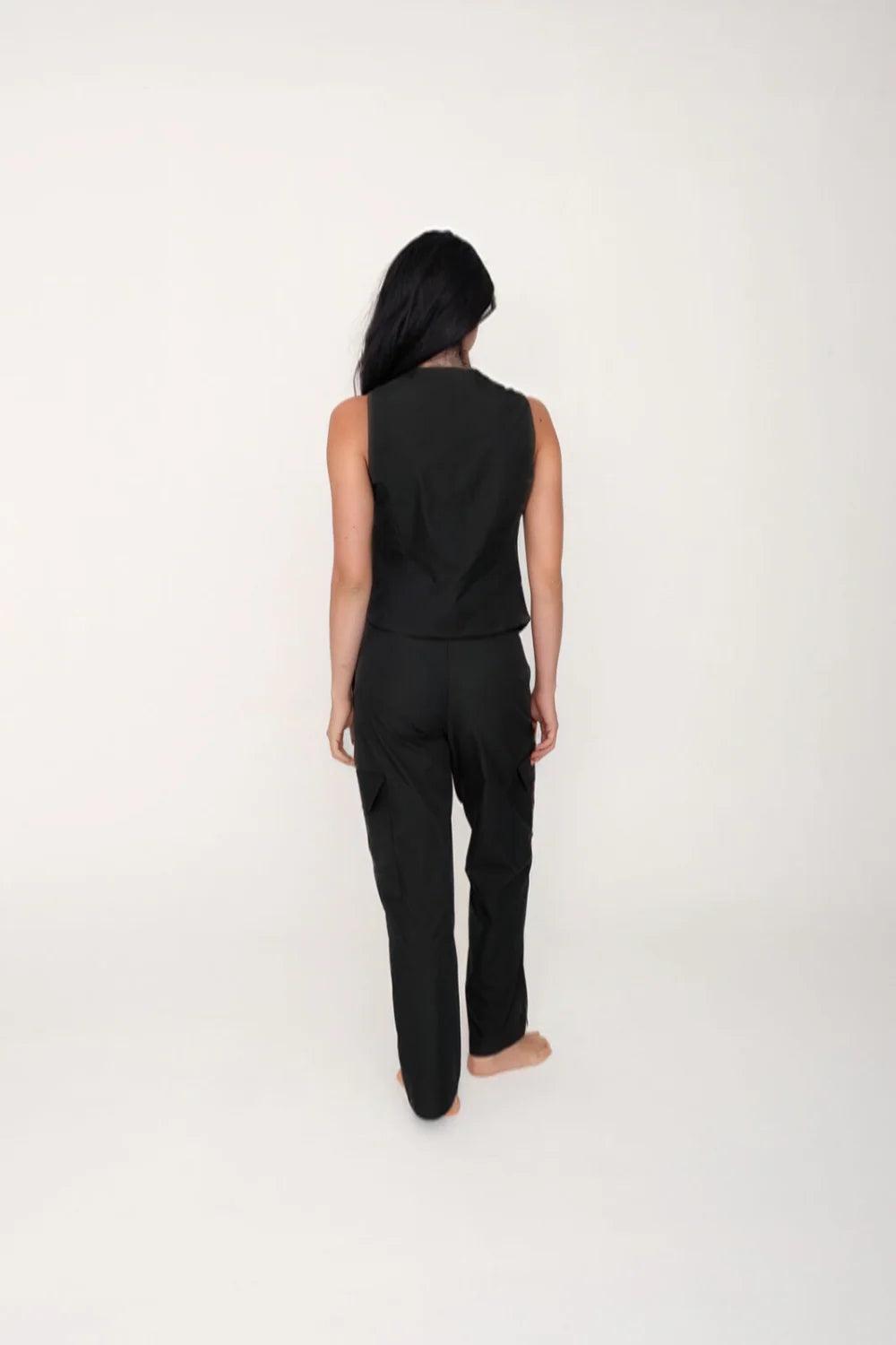 Person wearing a black sleeveless top and pants on a white background