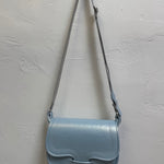 Light blue handbag with a strap on a light gray background