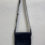 Navy blue leather crossbody bag on a light gray textured background