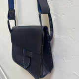 Navy blue leather bag with a strap on a light gray background