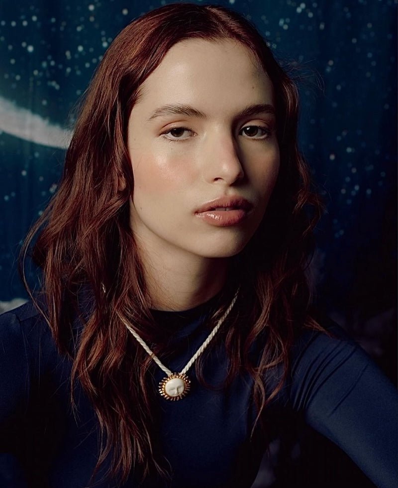 Image of a woman wearing a necklace with the sun on it. The purpose of this image is to highlight the necklace by Pajarolimon jewelry because it is for sale at EVAMAIA Boutique in Studio City, CA.