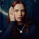 Image of a woman wearing a necklace with the sun on it and two oversized rings. The purpose of this image is to highlight the Pajarolimon jewelry because it is for sale at EVAMAIA Boutique in Studio City, CA.