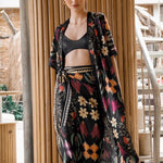 Image of a woman wearing a black skirt and matching kimono with bright flowers. The purpose of this image is to highlight the skirt, which is for sale at EVAMAIA boutique in Studio City, CA.