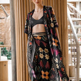 Image of a woman wearing a black skirt and matching kimono with bright flowers. The purpose of this image is to highlight the skirt, which is for sale at EVAMAIA boutique in Studio City, CA.