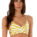 Woman wearing a bikini top with white and yellow animal print. She's standing against a white background. The purpose of this image is to highlight the swimsuit.