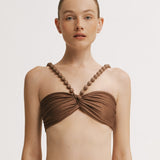 Woman wearing a brown bikini top with beaded straps on a white background.