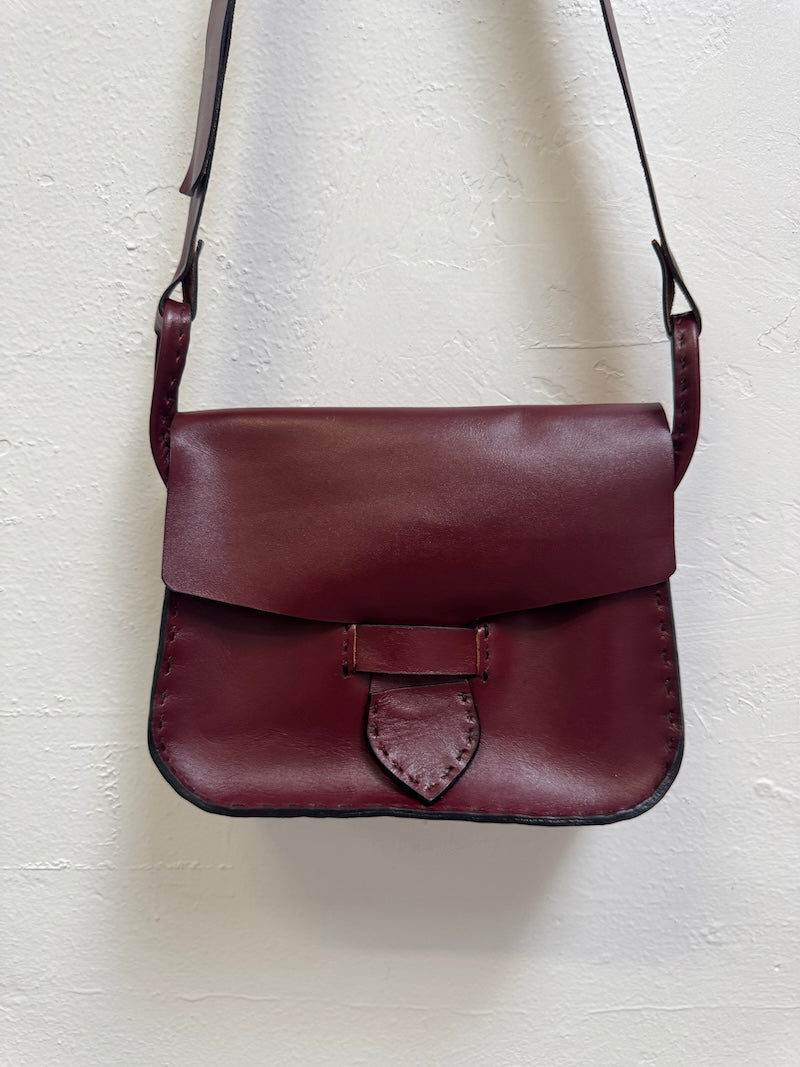 Burgundy leather bag on a light textured surface
