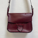 Burgundy leather bag on a light textured surface