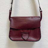 Burgundy leather bag on a light textured surface