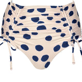 White swimsuit bottom with blue polka dots. It's on a white background. The purpose of this image is to highlight the bikini because it's for sale at EVAMAIA Boutique.
