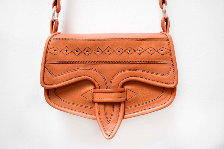 A brown crossbody leather bag with geometric embossing and a chain shoulder strap.