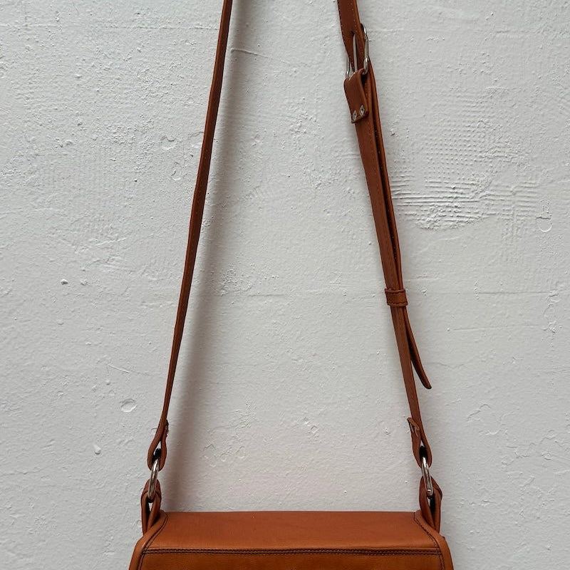 Image of a Honey Colored Western Style handbag hanging against a clear background background. The purpose of this image is to highlight the handbag.