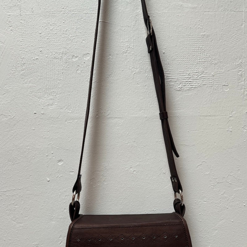 Image of a brown western Style handbag hanging against a clear background background. The purpose of this image is to highlight the handbag.