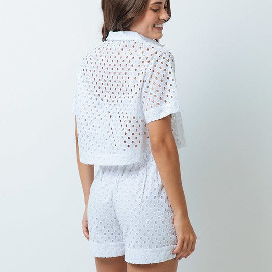 A woman is shown from the back wearing white shorts with small holes and a matching white top.