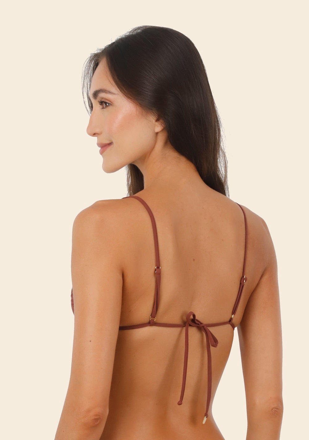 Woman wearing brown bikini against a beige background.