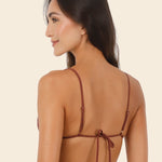 Woman wearing brown bikini against a beige background.