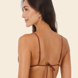 Woman wearing brown bikini against a beige background.