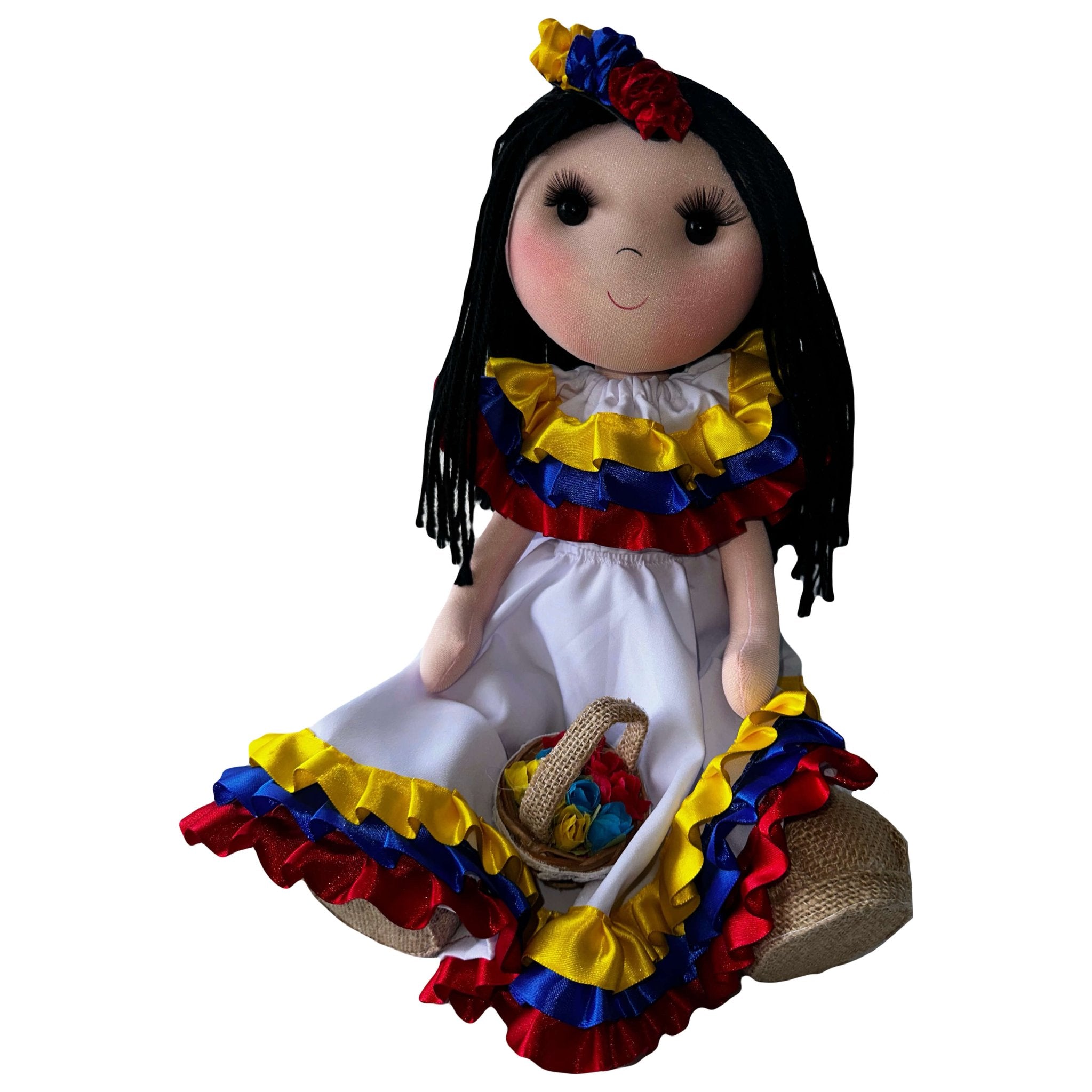 Rag Doll handmade in Colombia. She is wearing a white dress adorned with ruffles in colombian colors. She has straight hair, has a little colombian colored flower hair accessory. She is sitting with a basket of flowers.