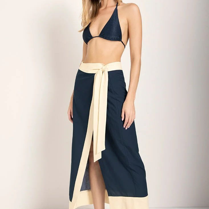 Image of a woman wearing a swimsuit top with a cover up skirt. The model is looking at the camera and standing against a white background. The purpose of this image is to show the skirt.