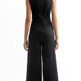 Back of a woman wearing a black jumpsuit with a cutout on the front. She's against a white background. The purpose of this image is to highlight the jumpsuit, which is for sale at EVAMAIA Boutique, in Studio City, CA.
