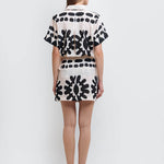 Back of a model wearing a stylish black and white abstract print shirt and skirt set made from high-quality polyester with a linen-like feel