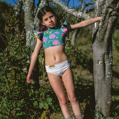 Girl wearing colorful two-piece swimsuit with floral pattern in a forest.