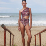 Woman in a patterned swimsuit standing on a beach with ocean in the background