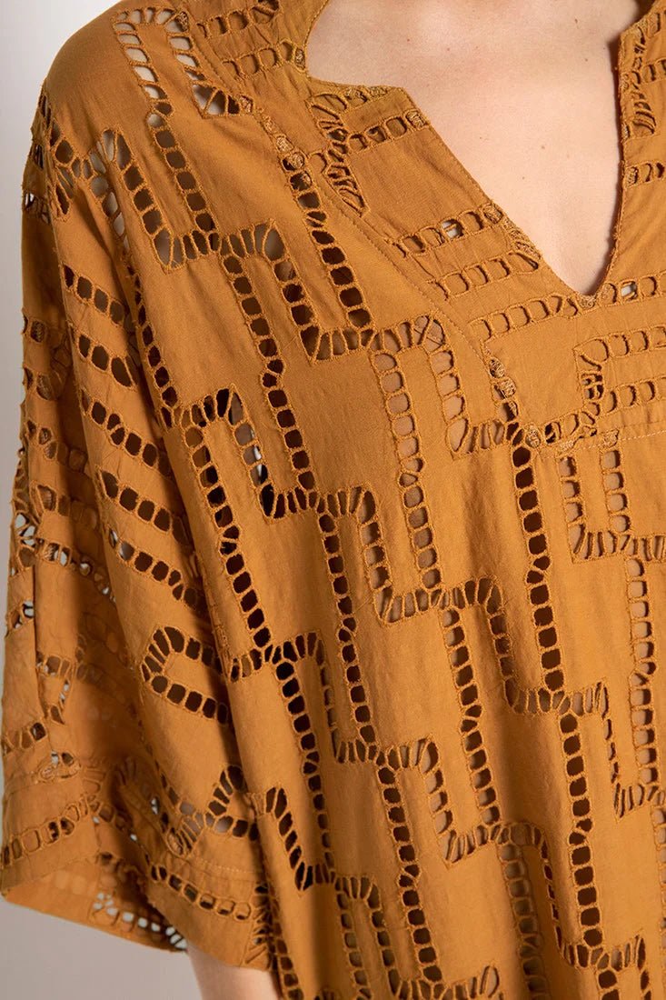 Close up image of a woman wearing a rust-colored dress. The purpose of this image is to show the embroidery details of the tunic dress.
