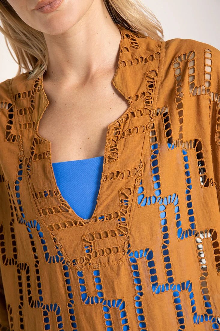 Close up image of a woman wearing a rust-colored dress. The purpose of this image is to show the embroidery details of the tunic dress.