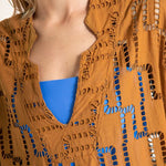 Close up image of a woman wearing a rust-colored dress. The purpose of this image is to show the embroidery details of the tunic dress.