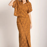 Image of a woman wearing sunglasses and an embroidered set. She is looking to the side. The purpose of this image is to highlight the skirt and shirt.