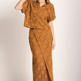 Image of a woman wearing sunglasses and an embroidered set. She is looking to the side. The purpose of this image is to highlight the skirt and shirt.