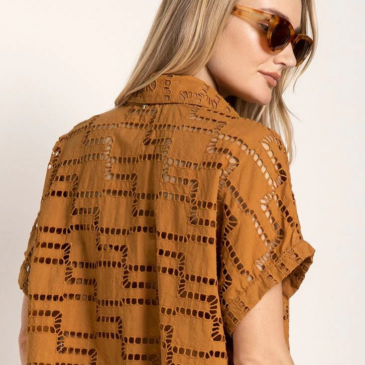 Close up image of a woman wearing sunglasses and an embroidered shirt. She's against a white background. The purpose of this image is to highlight the shirt.