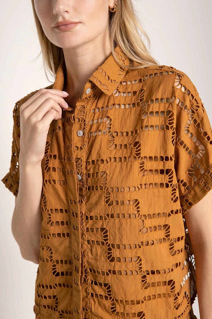 Close up image of a woman wearing an embroidered shirt. She's against a white background. The purpose of this image is to highlight the shirt.