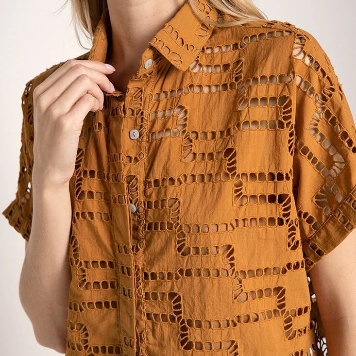 Close up image of a woman wearing an embroidered shirt. She's against a white background. The purpose of this image is to highlight the shirt.
